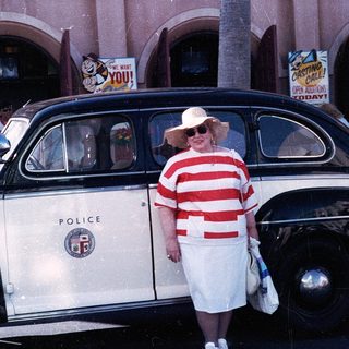 Vintage police car with woman in retro dress posing.