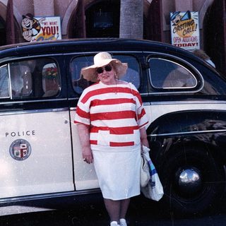 Vintage police car with woman in retro dress posing.