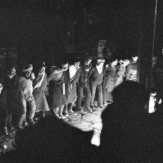 Group of men standing in line at night.