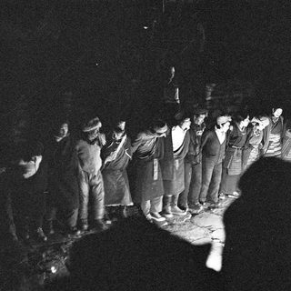 Group of people standing in line at night.