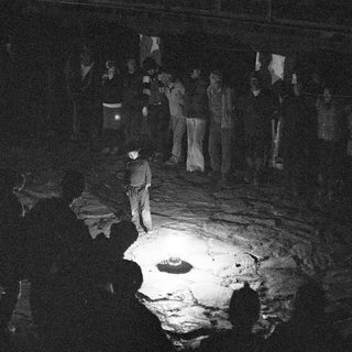 Dark room with people gathered around illuminated crater.