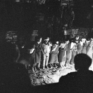 Group of people gathered in a dimly lit outdoor area.