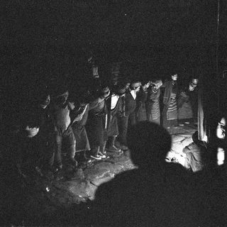 Group gathered around nighttime campfire.