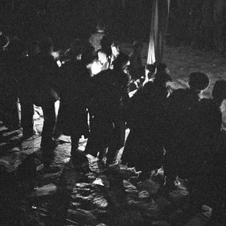 Group of people gathered around a bonfire at night.