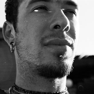 Close-up of a bearded man with facial piercings.