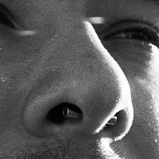 Close-up of a bearded man with facial piercings.