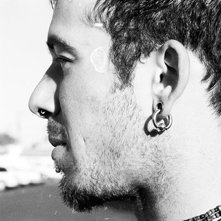 Side profile of bearded man with ear piercing.