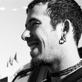 Smiling man with nose ring and beaded necklace.