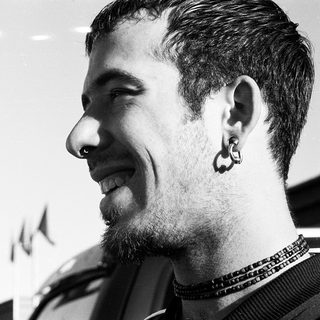 Smiling man with nose ring and beaded necklace.