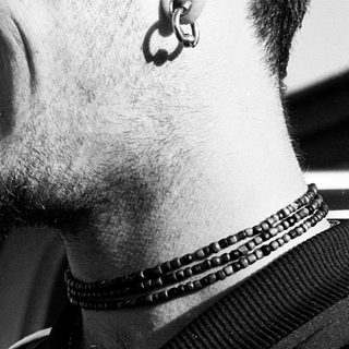 Smiling man with nose ring and beaded necklace.