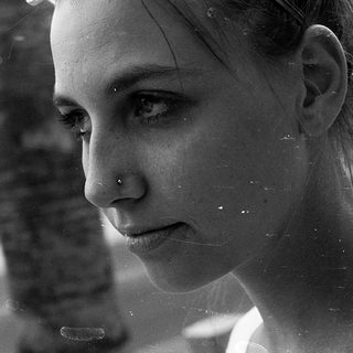 Reflection of woman looking outside rainy window.