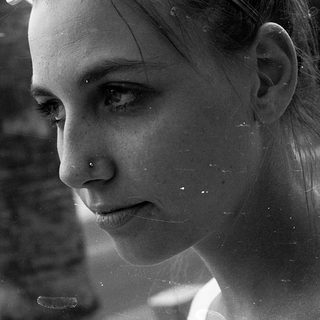 Reflection of woman looking outside rainy window.