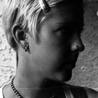 Short-haired person with nose ring and earring.