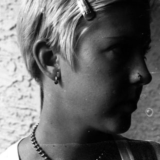 Short-haired person with nose ring and earring.