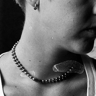 Young person with short hair wearing pearl necklace.