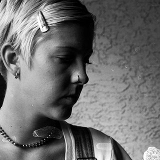 Young person with short hair wearing pearl necklace.