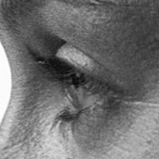 Close-up of person with tear on cheek.