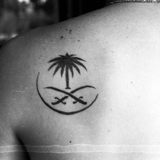 Temporary palm tree and crescent sword tattoo on shoulder.