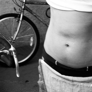 Person squatting near bicycle with rolled jeans.