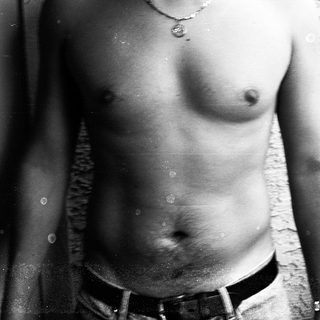 Shirtless person wearing belt indoors.