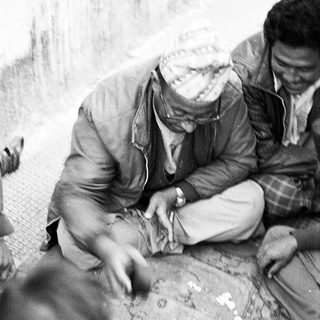 Two men playing traditional board game outdoors.
