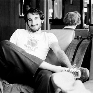 Young man in 1980s-style T-shirt posing indoors.
