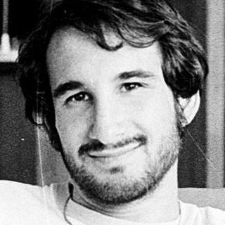 Young man in 1980s-style T-shirt posing indoors.