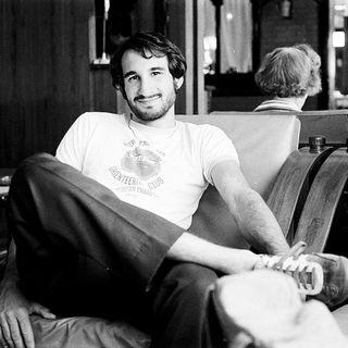 Young man in casual attire posing relaxed indoors.