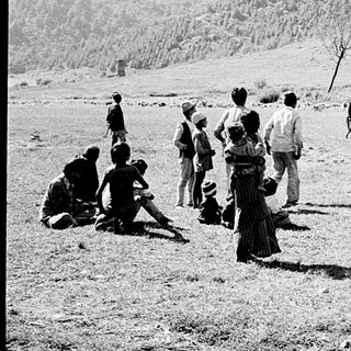 People gather near Royal Nepal Airways seaplane on grass airstrip.