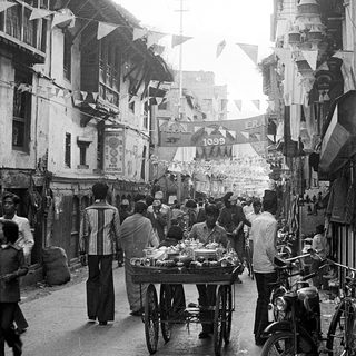 Busy street market with vendors, carts, and pedestrians.