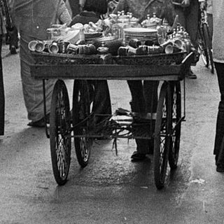 Busy street market with vendors, carts, and pedestrians.