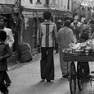 Busy street market with vendors, carts, and pedestrians.