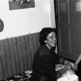 A woman and a young boy shaking hands indoors.