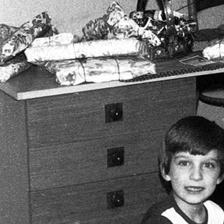 Boy playing with toy train set indoors.