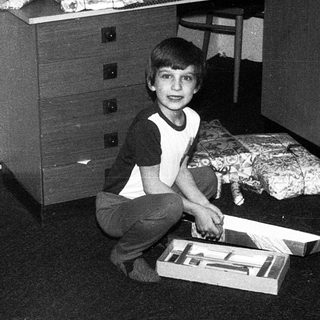 Boy playing with toy train set indoors.