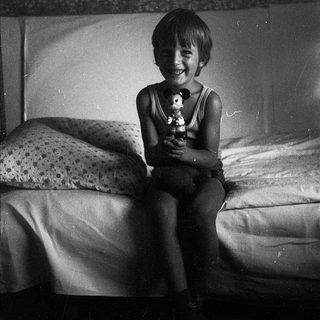 Happy child holding stuffed toy on bed.