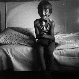Happy child holding stuffed toy on bed.