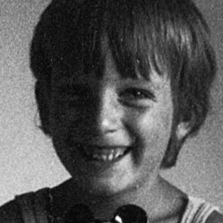 Happy child holding stuffed toy on bed.