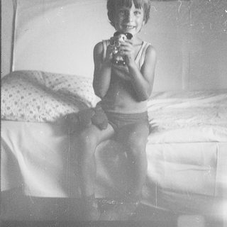 Young boy smiling while holding toy gun.