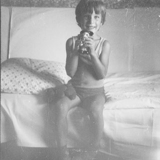 Young boy smiling while holding toy gun.