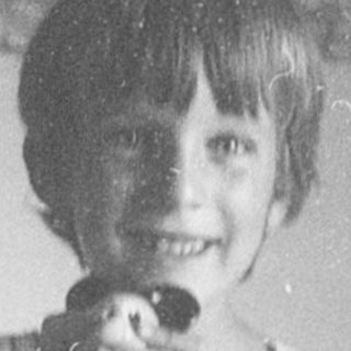 Young boy smiling while holding toy gun.