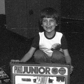 Child sitting on vintage Atari Junior arcade machine.