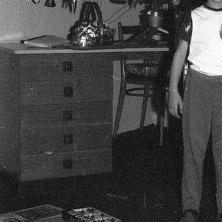 Young boy standing beside decorated Christmas tree.