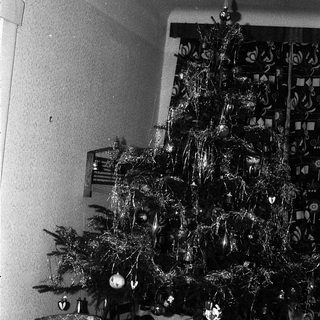 Vintage black-and-white Christmas tree with ornaments and gifts.