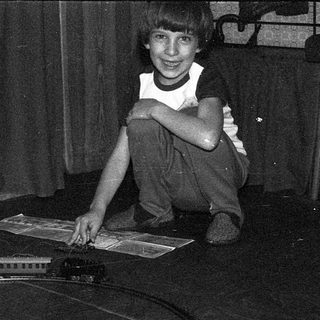 Boy playing with model train set indoors.
