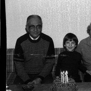 Family celebrating a birthday with candles on cake.