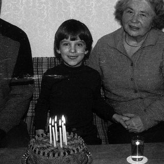 Family celebrating a birthday with candles on cake.