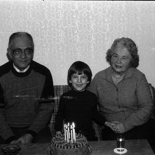 Family celebrating a birthday with candles on cake.