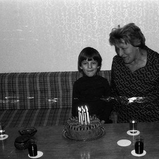 A woman and child blowing out birthday cake candles together.