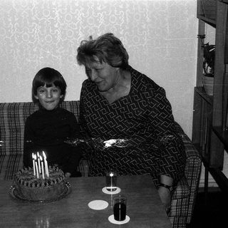 A woman and child blowing out birthday cake candles together.
